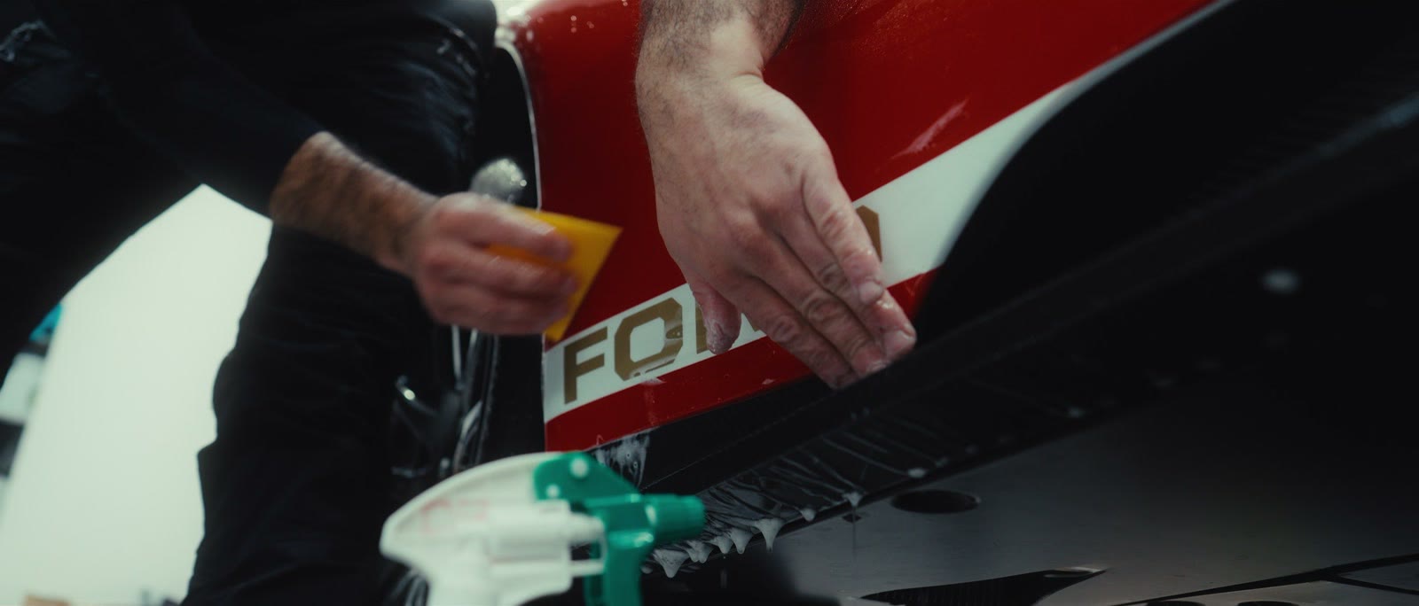 Les mains du poseur maroufflent le film sur le capot