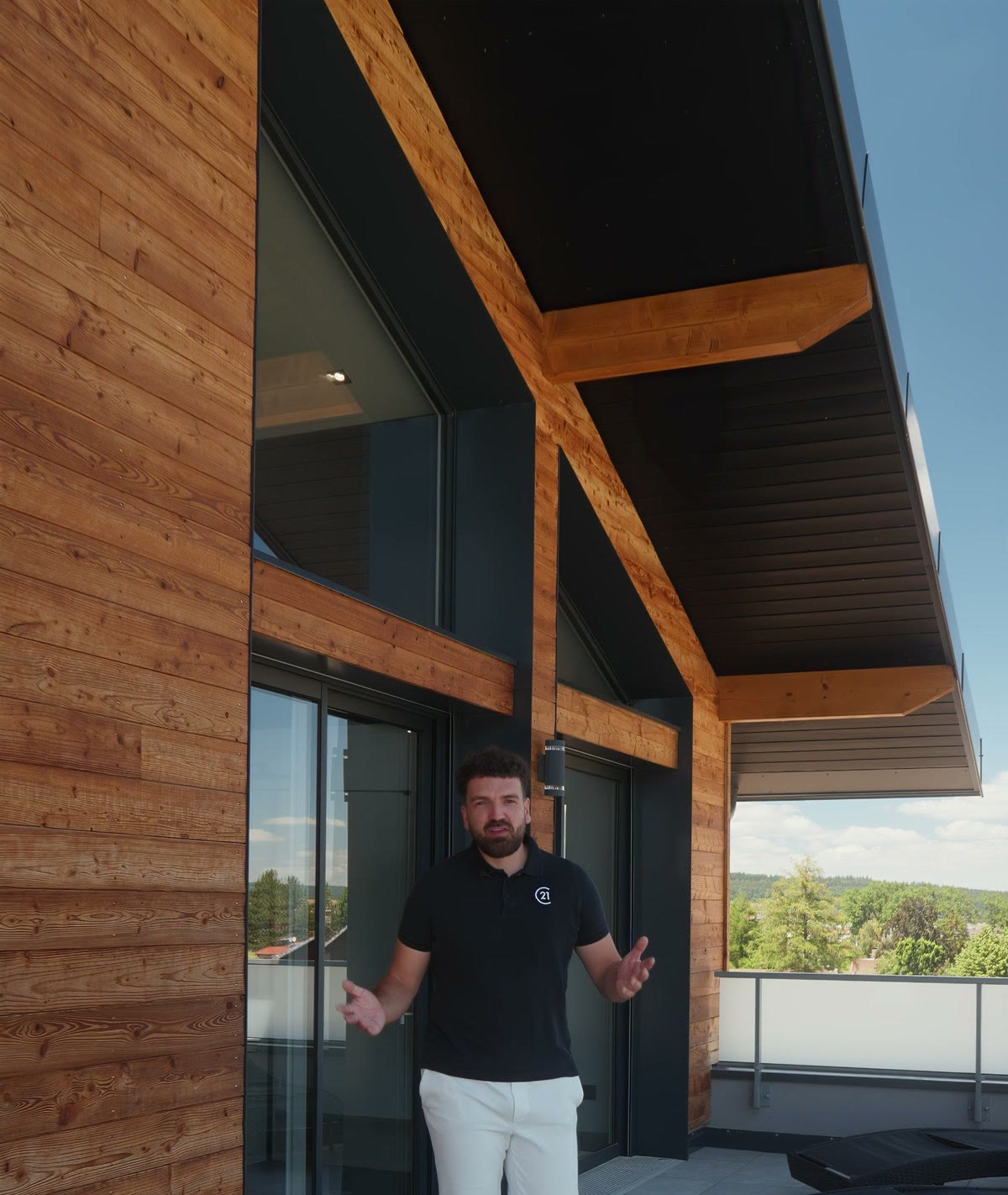 L’agent devant les baies vitrées, sous l’avancée en bois