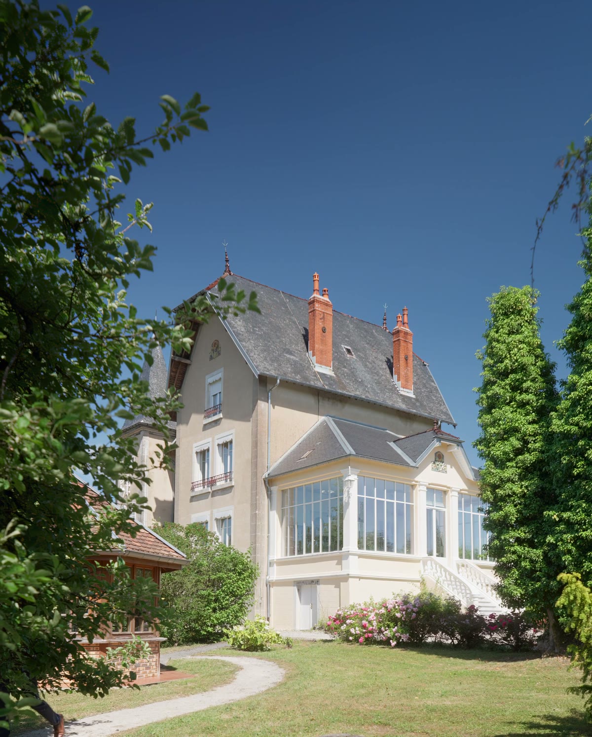 La façade et la tourelle en fin de journée, entre les arbres