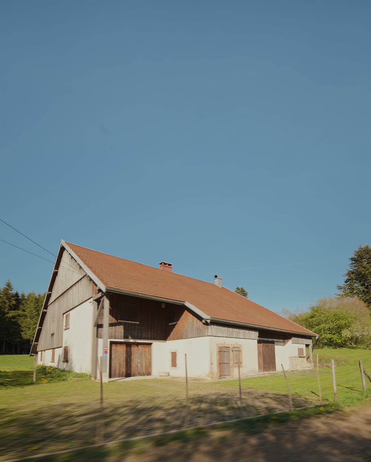La façade et son bardage de bois, depuis le pré