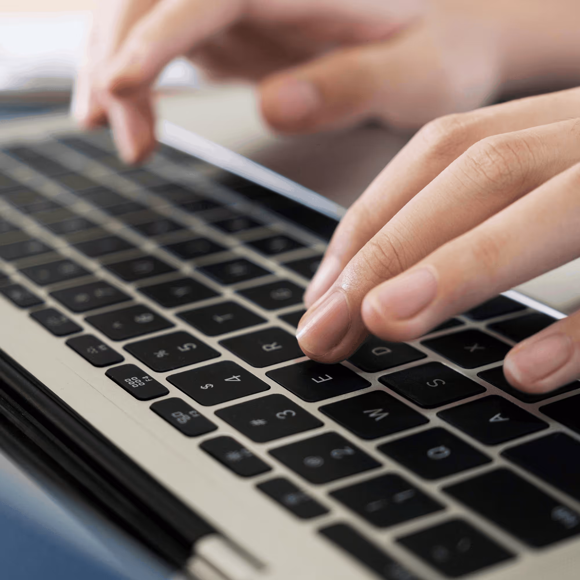 Doigts tapant sur un clavier d'ordinateur portable noir et argenté.