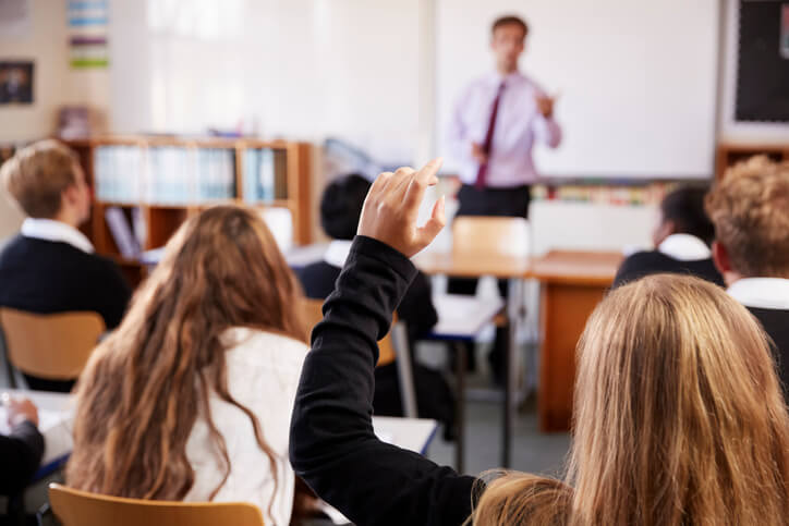 A private school student raising her hand in class.