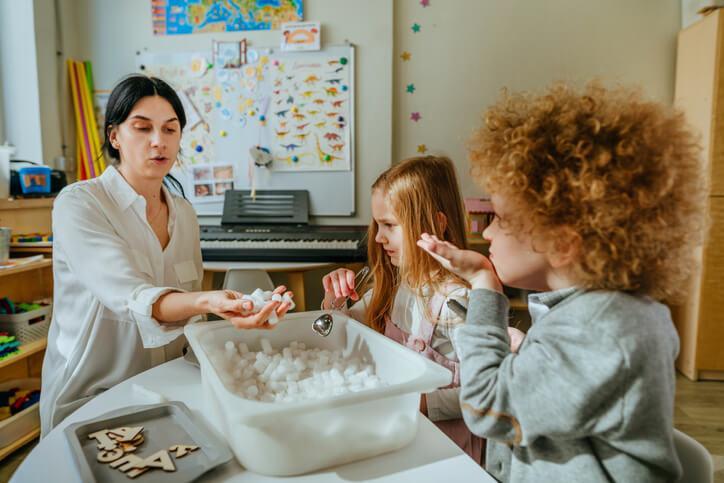 A duo of smiling pupils working on a sensory project with a teacher at our private school.