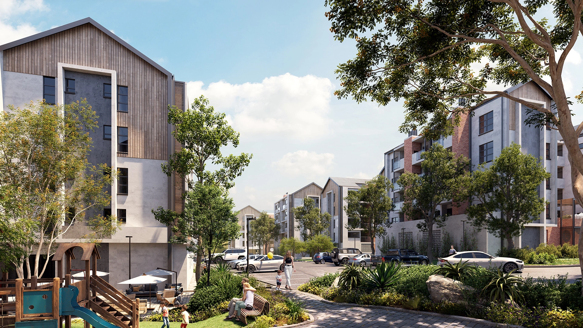 Modern residential complex with multi-story buildings, parking lot, greenery, playground, and people walking and sitting on benches under a blue sky.