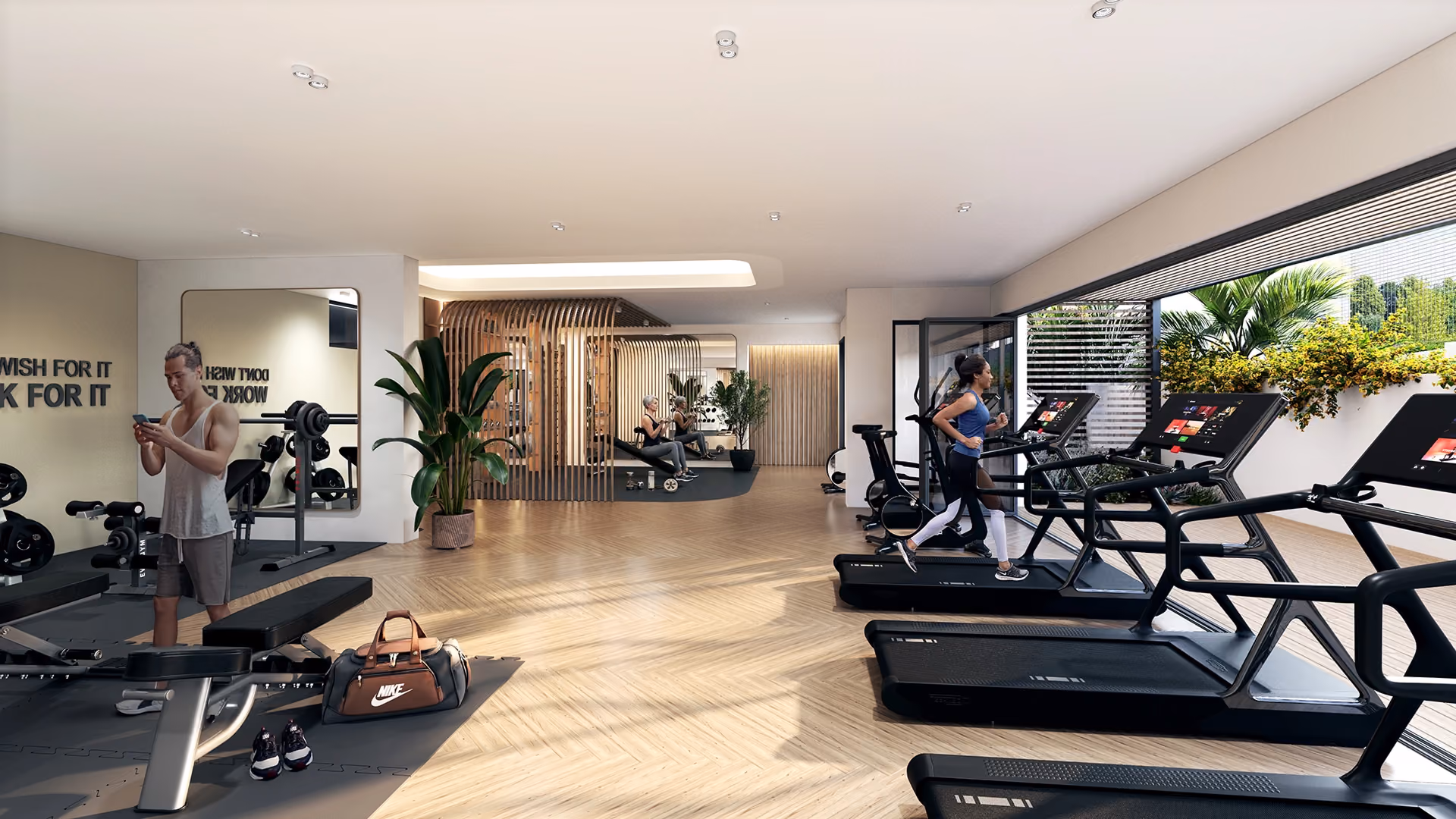 Modern gym with wooden flooring and large windows; a man checks his phone by weight benches, a woman runs on a treadmill, and two women exercise with dumbbells near a wooden slatted partition.
