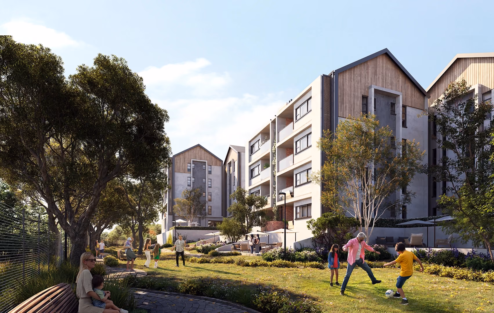 Modern apartment buildings with sloped roofs and an outdoor green space where people, including children and adults, are playing and socializing under trees.