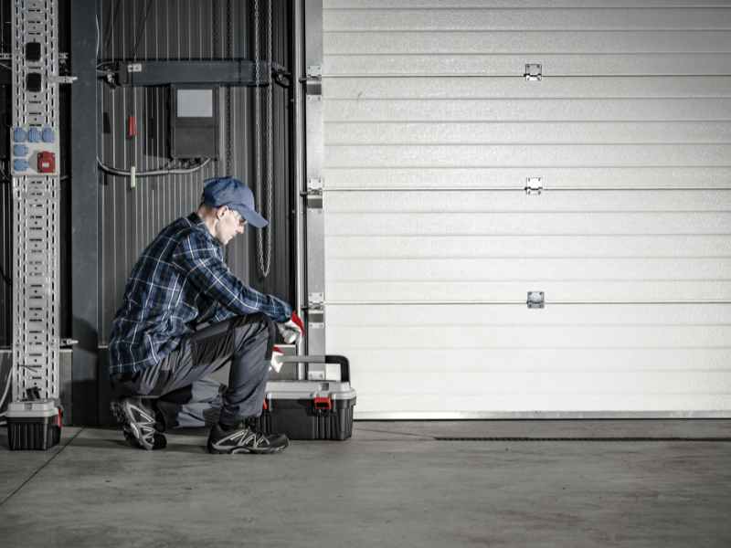 Contractor repairing a self-storage unit roll-up door