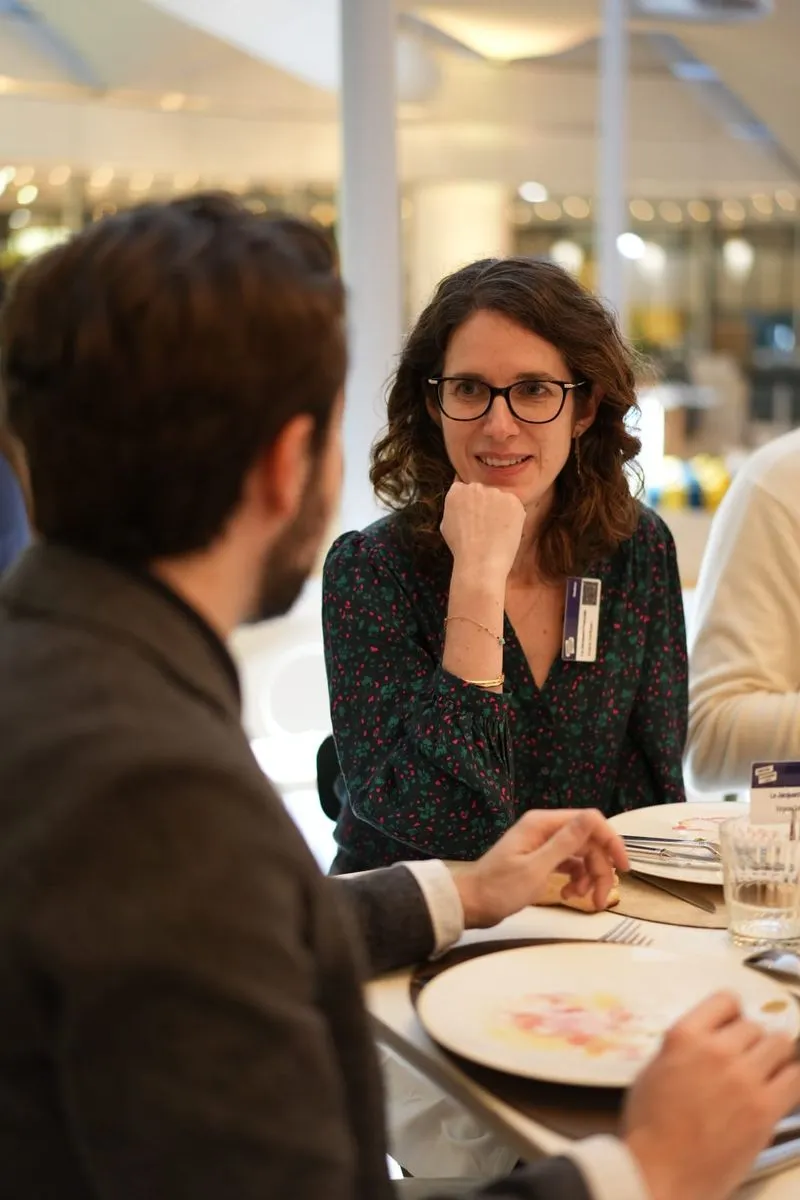 A woman with glasses smiles and listens to a man during a meal at a restaurant.