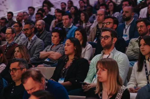 A diverse audience attentively listens to a speaker at a conference.