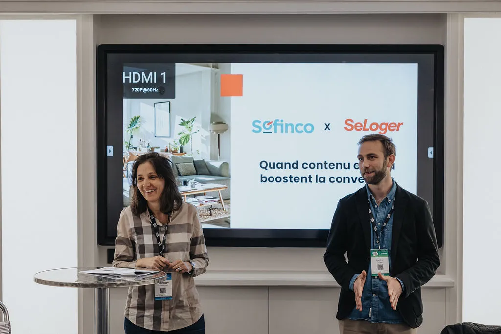 Two people stand in front of a screen displaying "SCFinco x SeLoger" during a presentation.