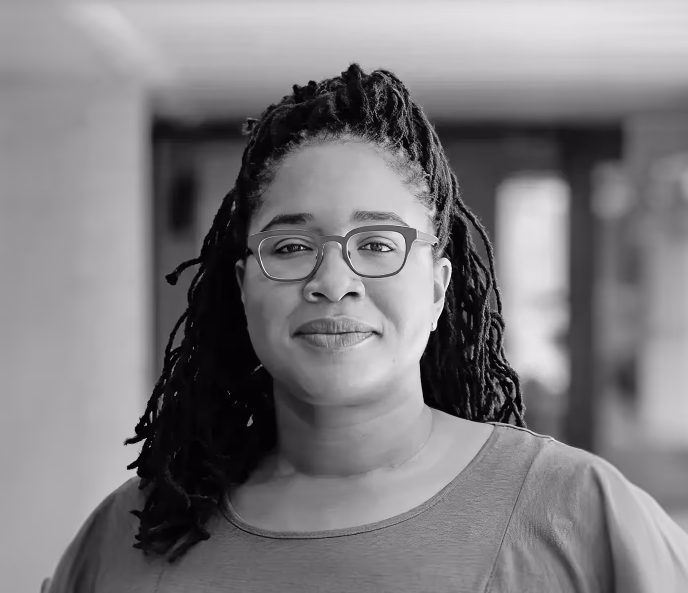 Black and white portrait of Jasmine McNealy standing in a hallway focused on privacy and public policy research.