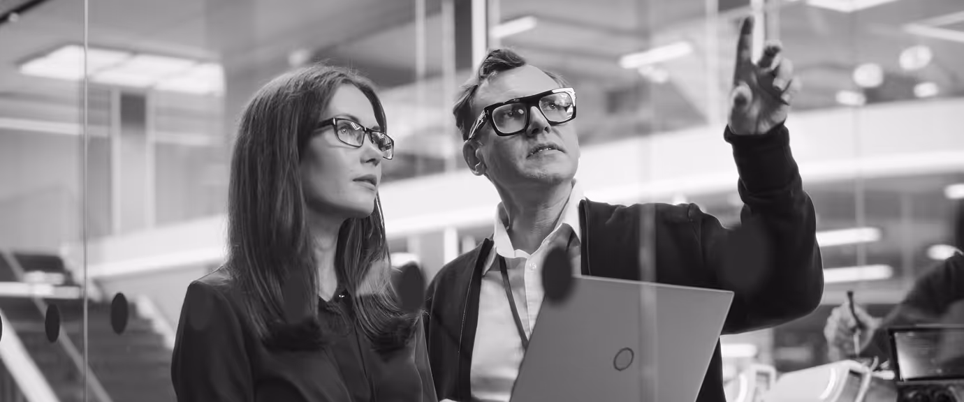 Two professionals reviewing information on a laptop while discussing privacy and policy decisions.