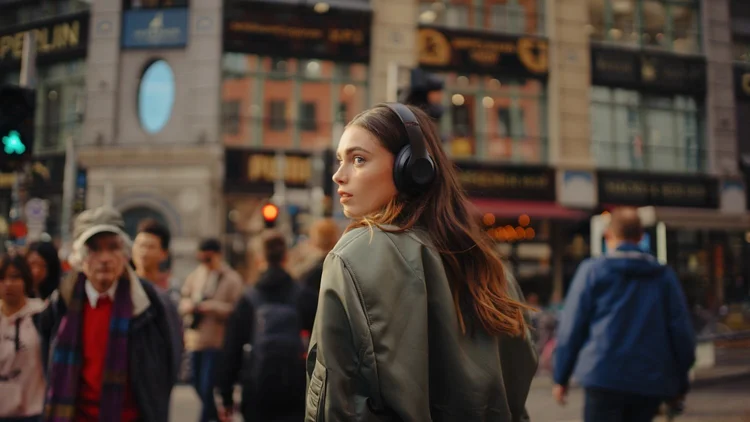 Girl with headphones on the street surrounded by people