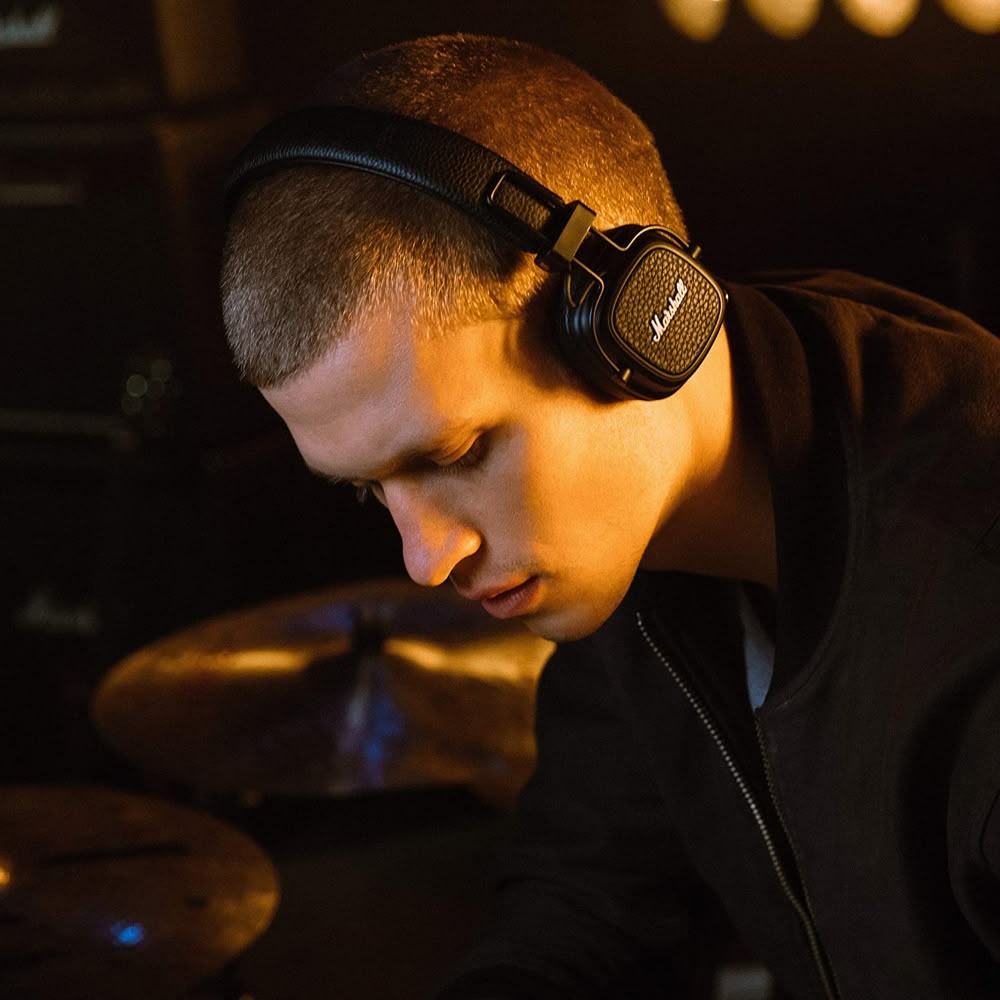 Young man listening to music with headphones on a couch.