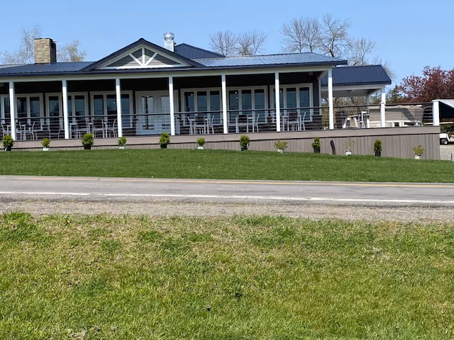 A large white house with a blue roof and a white fence.