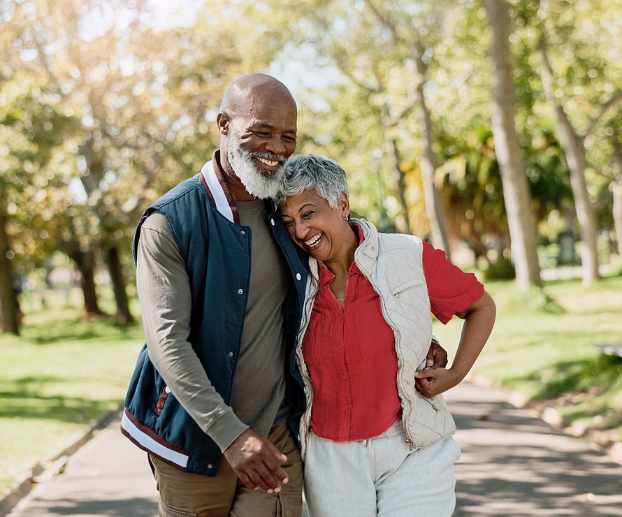 Retired couple embracing while walking in a park