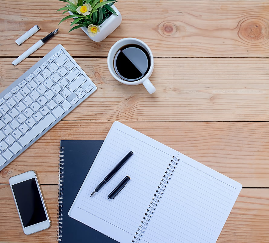 Desk with journal, keyboard, phone and coffee