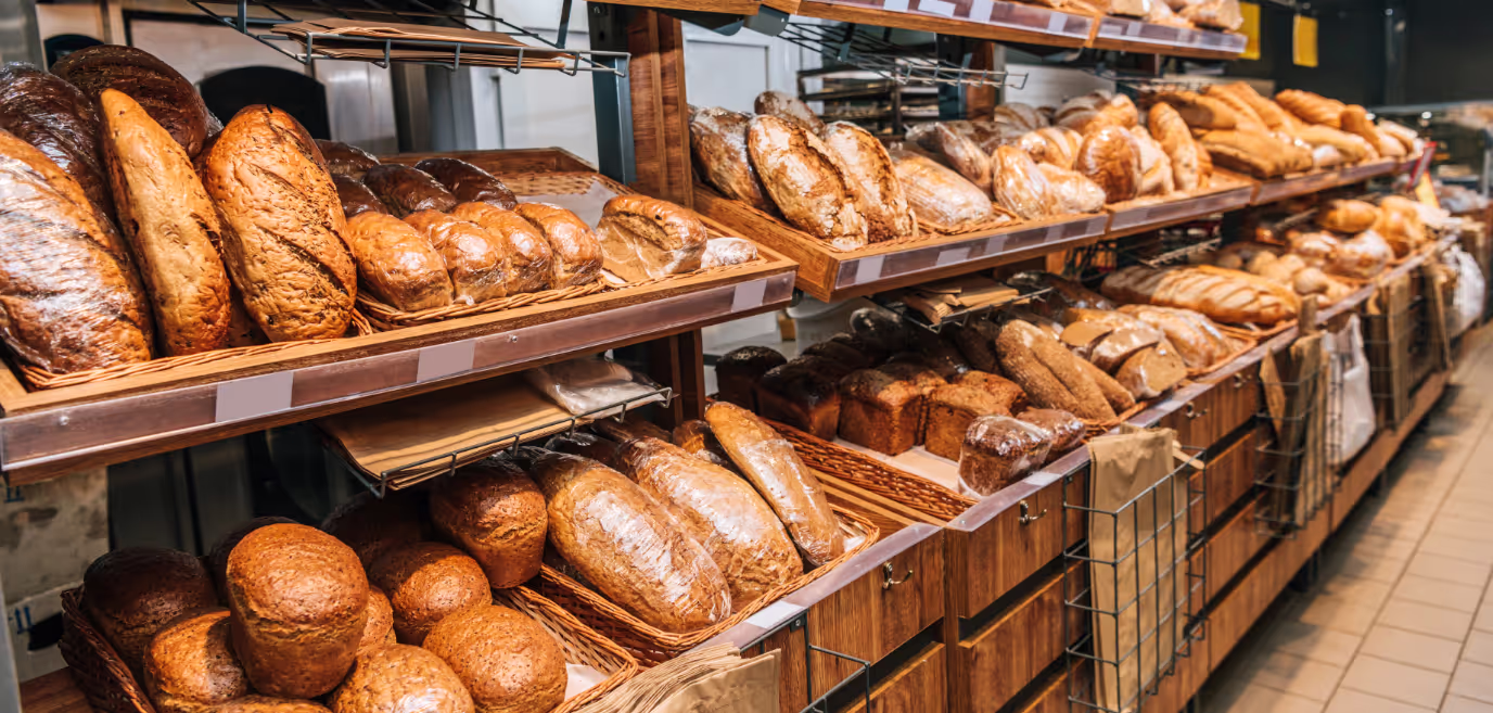 a variety of different types of loaves of bread in baskets in a bakery