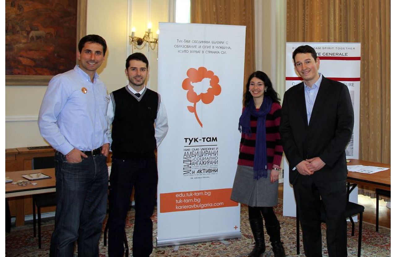 Four people standing beside a banner with Bulgarian text in a formal room.
