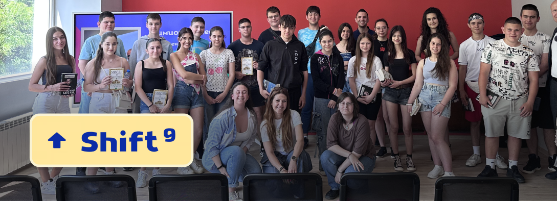 Group of teenagers and young adults posing indoors with books and smiling toward the camera.
