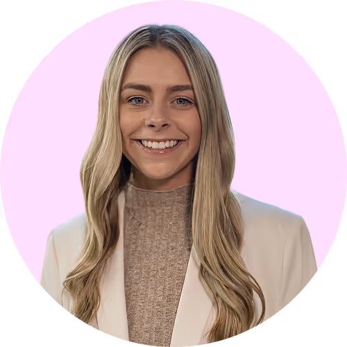 Smiling young woman with long blonde hair wearing a beige blazer and knit top against a light pink circular background.