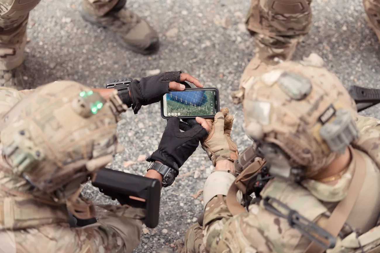 Military personnel using digital technology during specialist field operations.