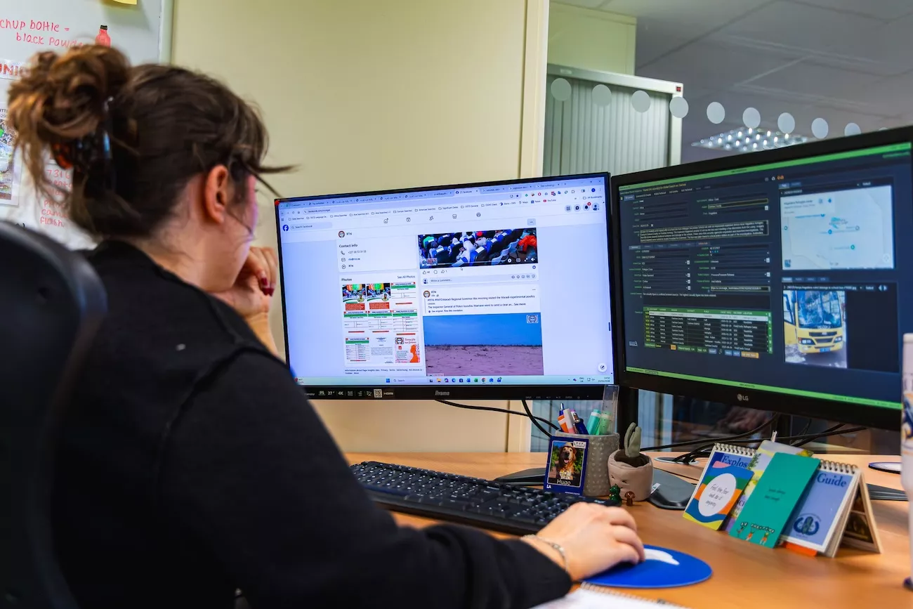 Intelligence analyst monitoring social media sources to verify threat intelligence for corporate risk clients