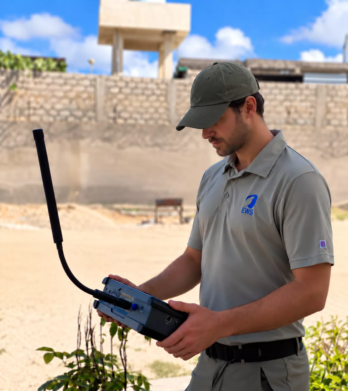 EWS field technician operating specialist electronic survey equipment on-site during an outdoor assessment.