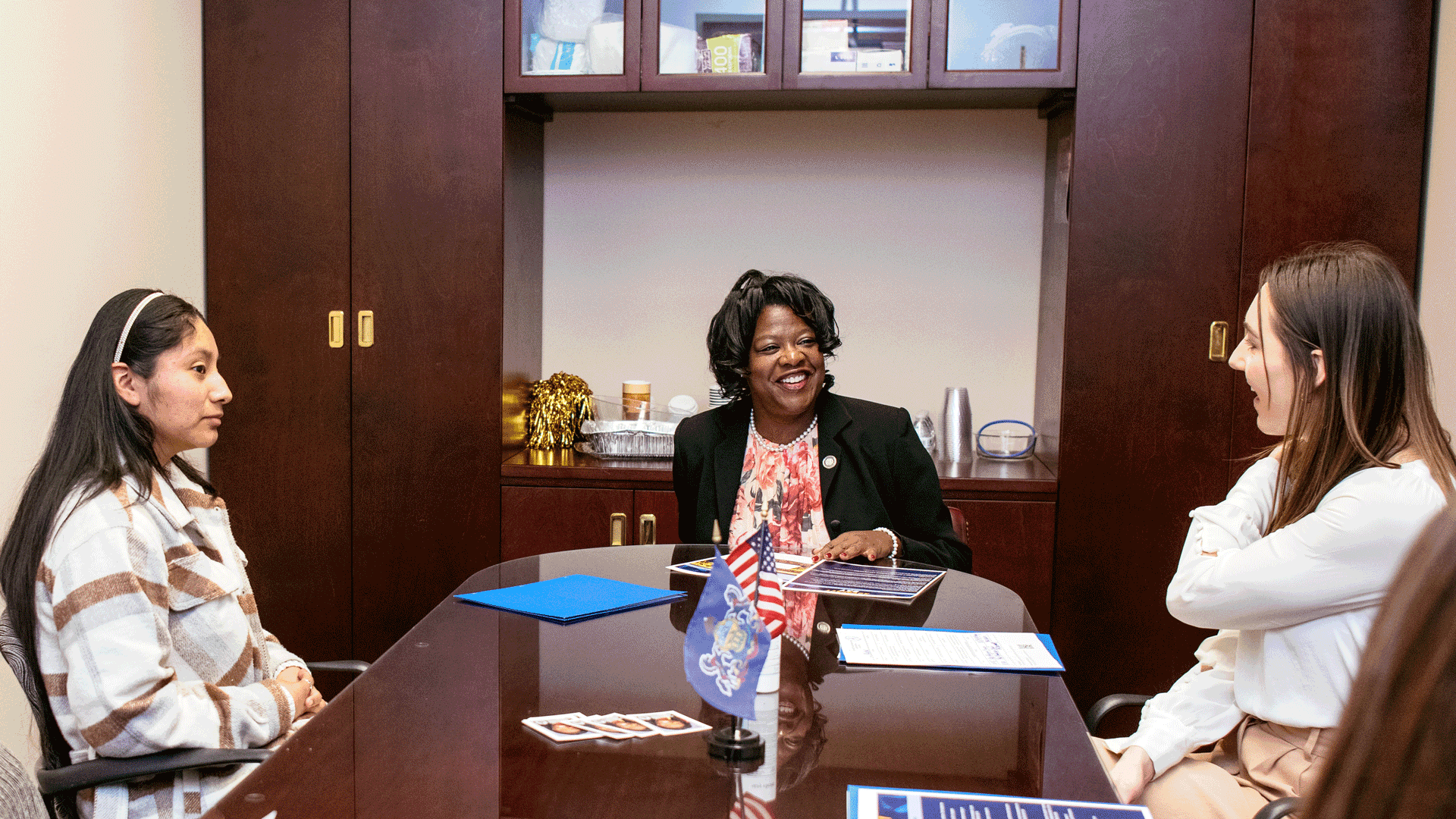 Philadelphia State Representative Regina Young speaks with two young women in her office with PEDC's collateral on the table. This photo is from PEDC's 2025 Advocacy Day.