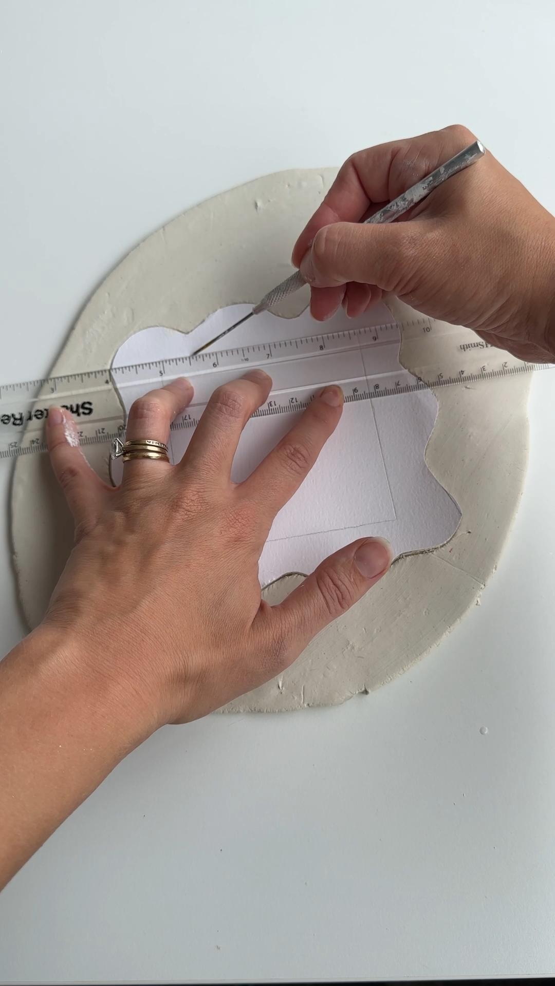 Using a ruler and craft knife to measure and mark an air dry clay light switch cover template on rolled clay.