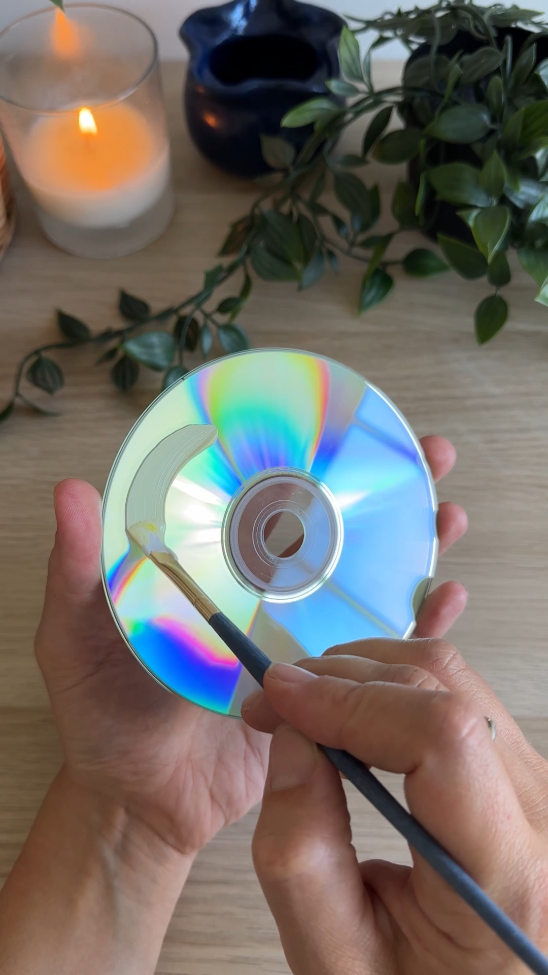 hand painting a base coat onto an old cd for a diy upcycled cd coaster craft