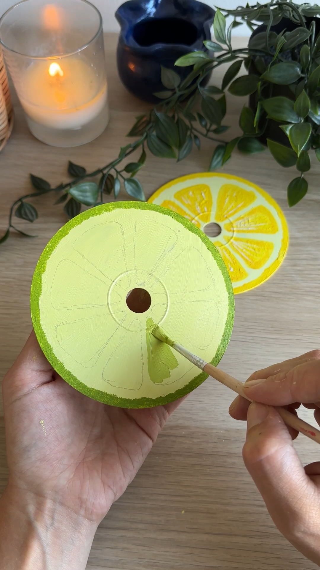 hand painting green lime segments onto an upcycled cd to create a diy lime coaster