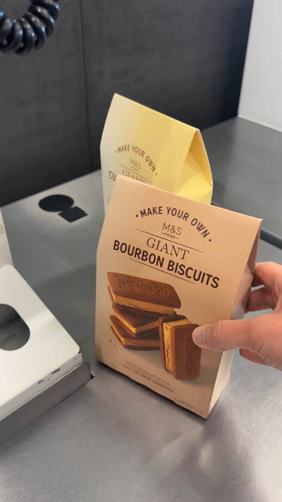 hand holding the m&s giant bourbon biscuit kit box before opening