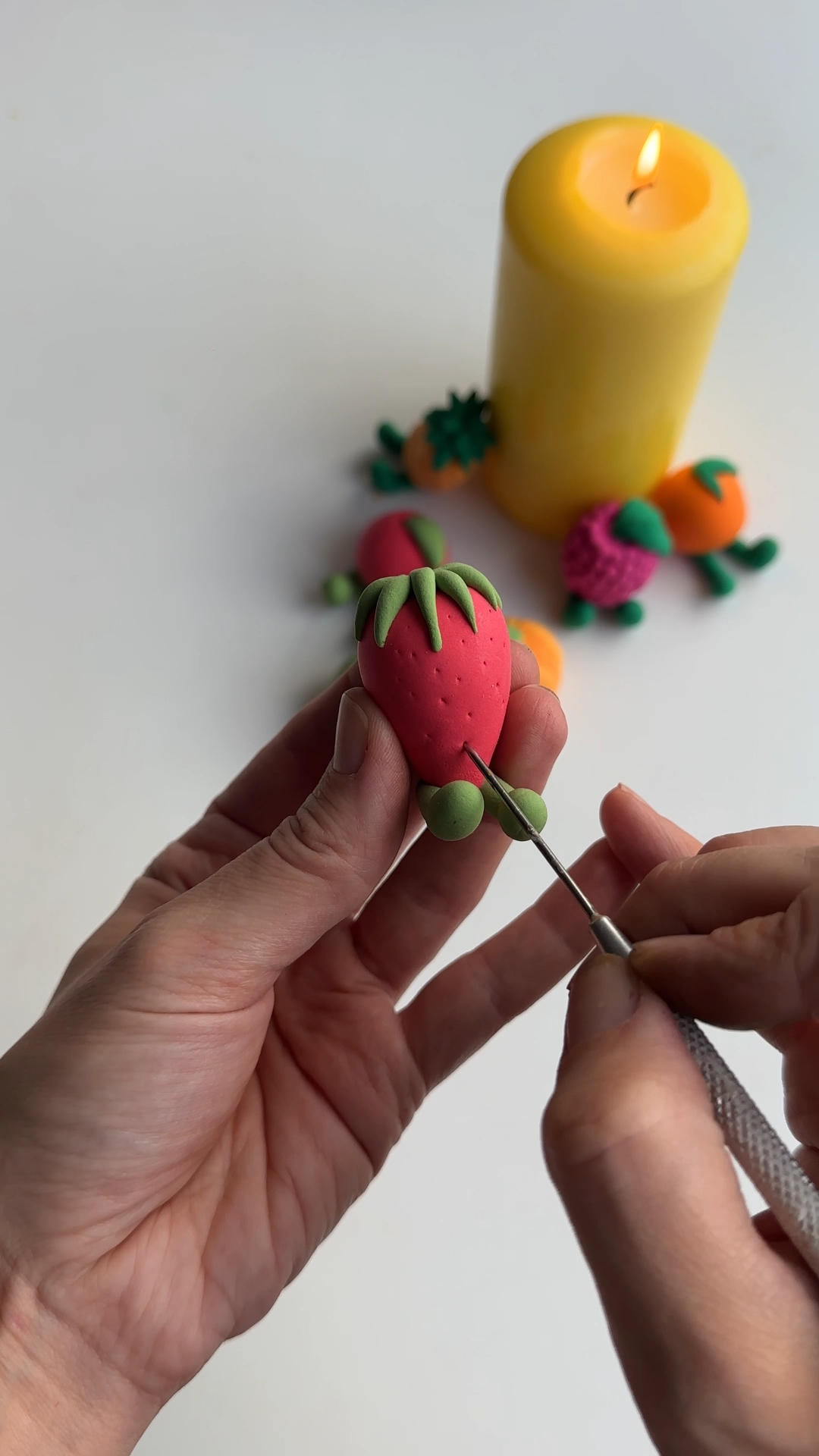 needle tool adding small seed dots to strawberry clay magnet