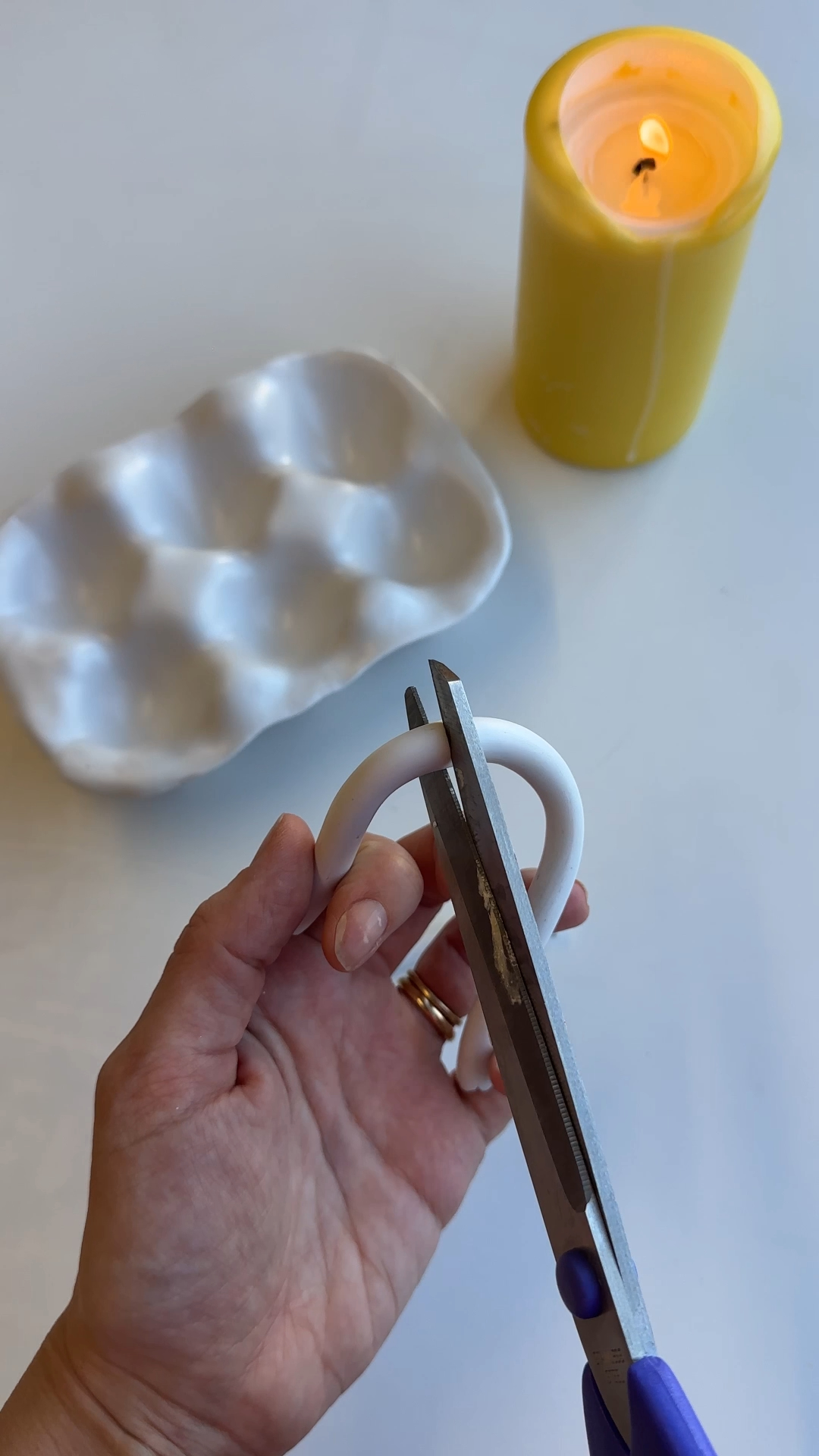 attaching rolled clay handles to ends of egg tray