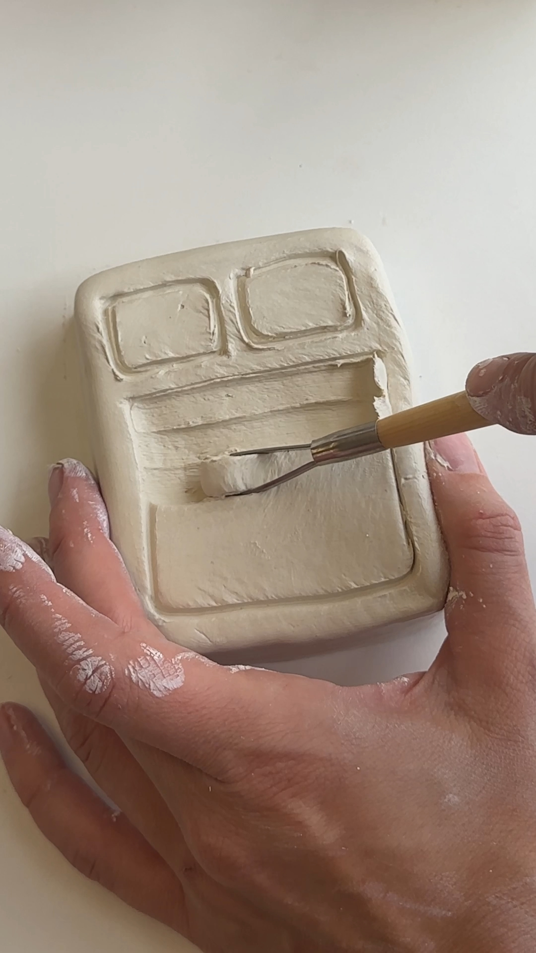 carving soft pillow and duvet details into clay bed shape