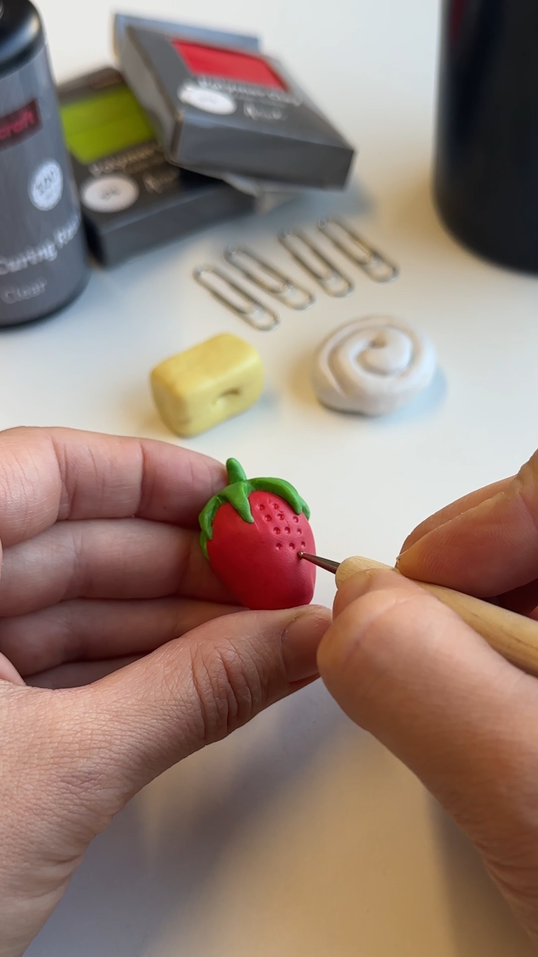 tool carving texture into clay strawberry