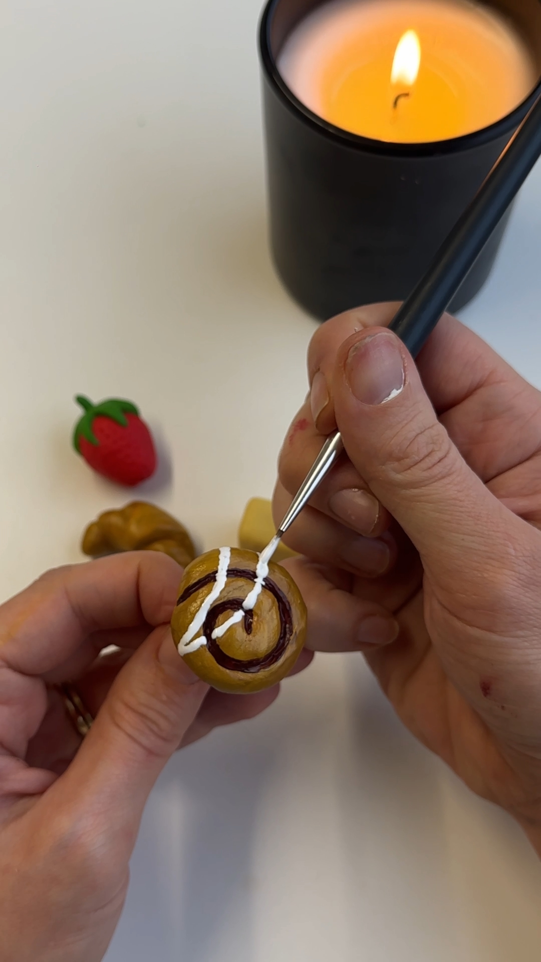 hand painting details onto miniature clay swirl bookmark