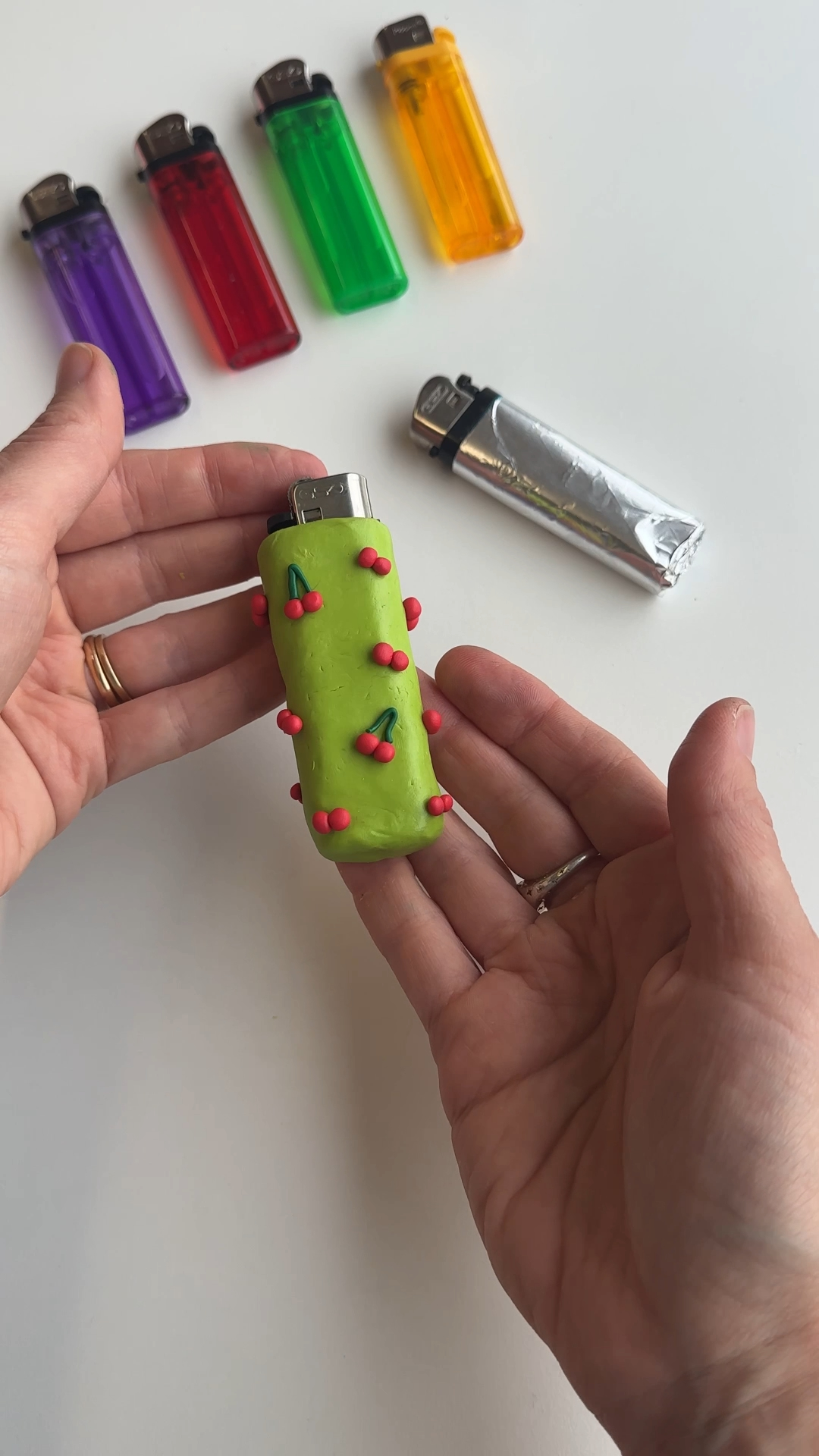 pressing small cherry shapes onto green clay lighter case surface