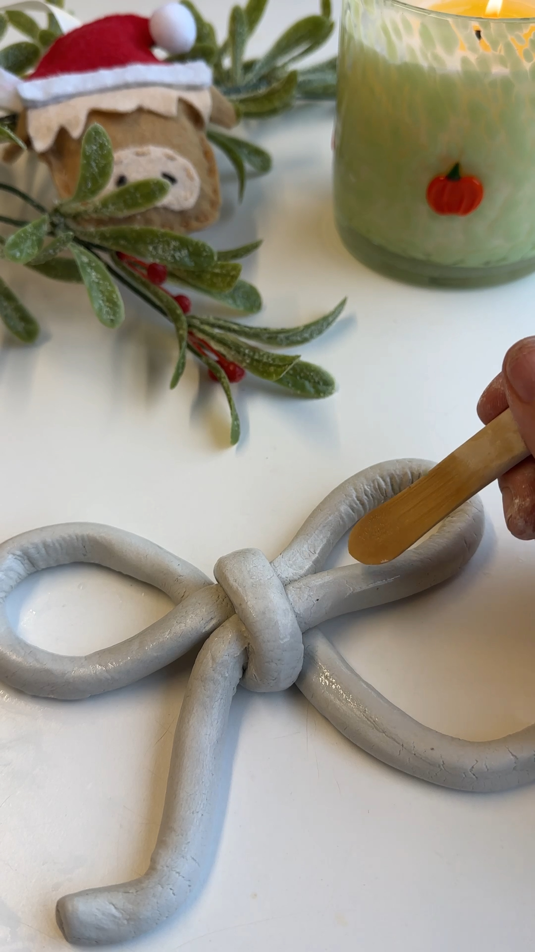 fingers smoothing edges and refining air dry clay bow shape