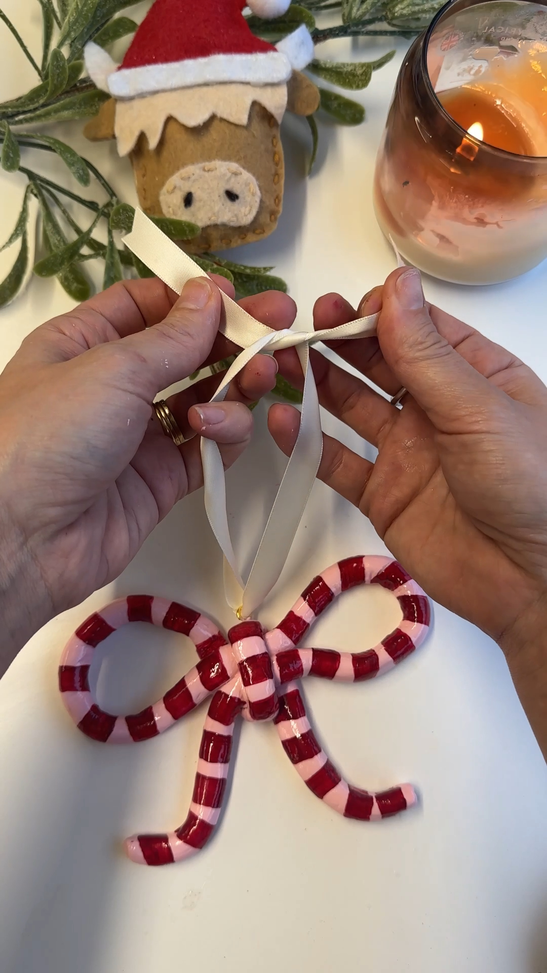 threading ribbon through finished glossy clay bow decoration