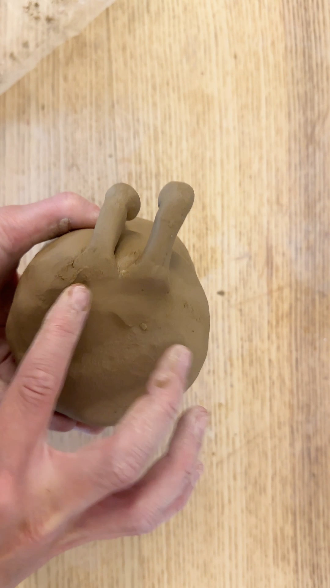 two small rounded clay legs being attached and blended onto the base of the cake