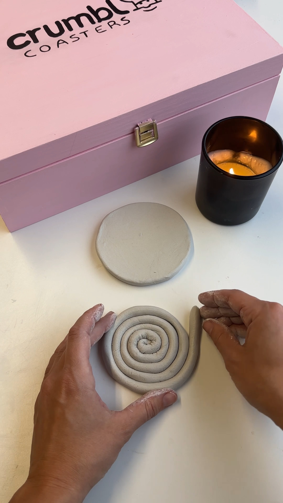 hands shaping air dry clay into a round cookie coaster