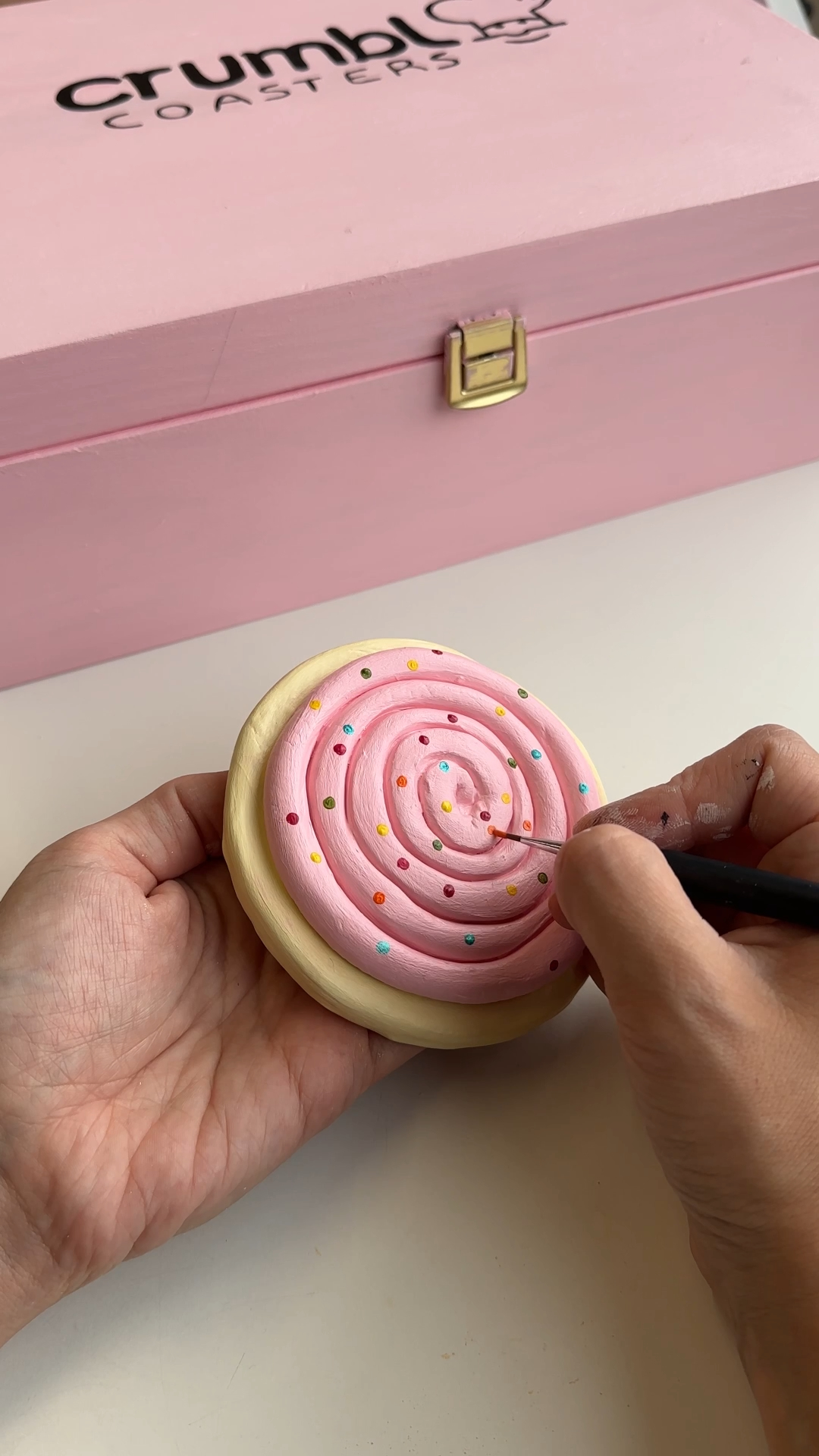 painting pink icing and sprinkles on an air dry clay cookie coaster