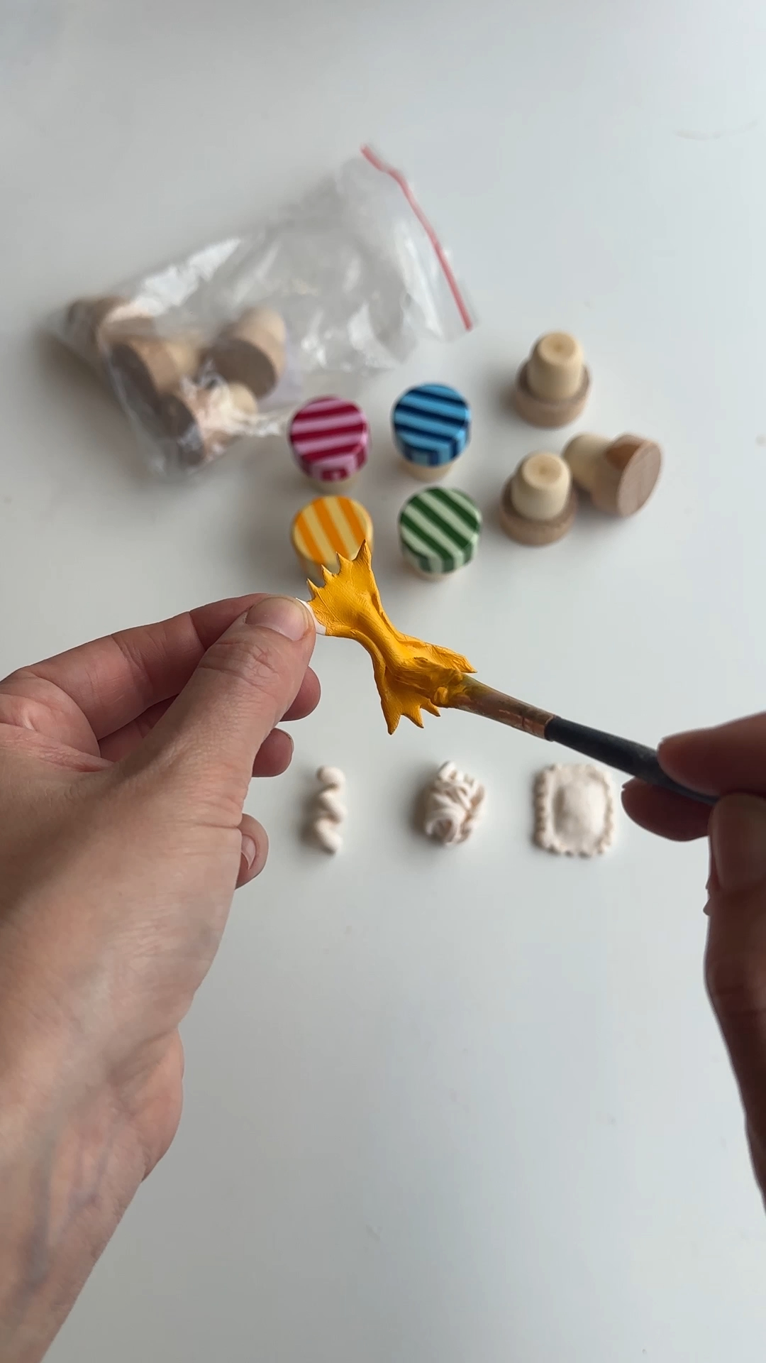 baked polymer clay pasta shapes being painted with warm pasta yellow acrylic