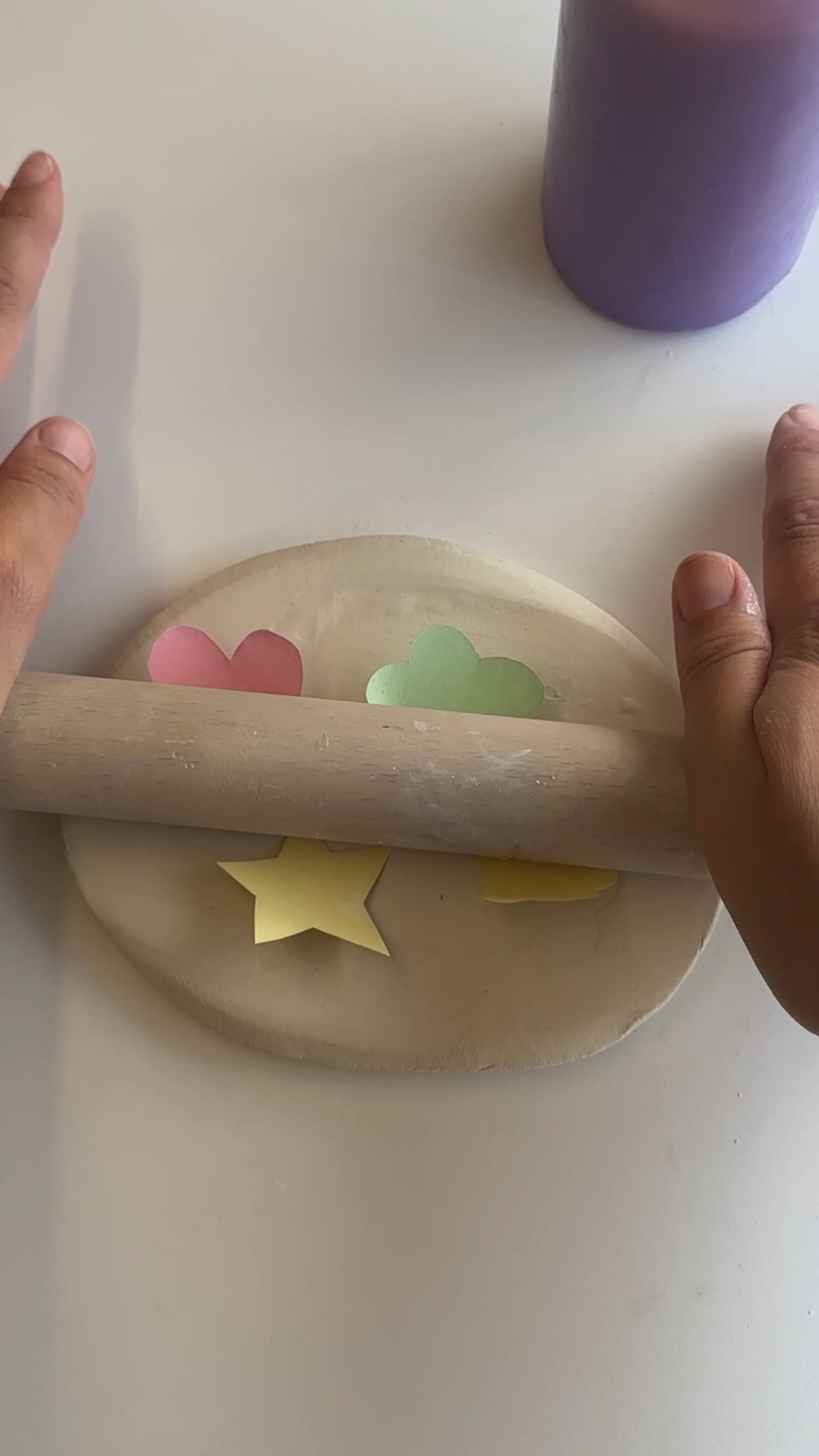 hands rolling a heart, flower and star shape into a rolled slab of air dry clay