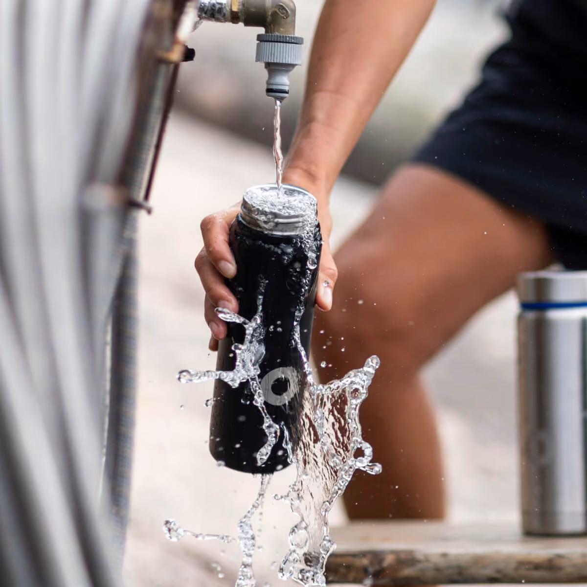 Person filling a reusable bottle from a kitchen tap