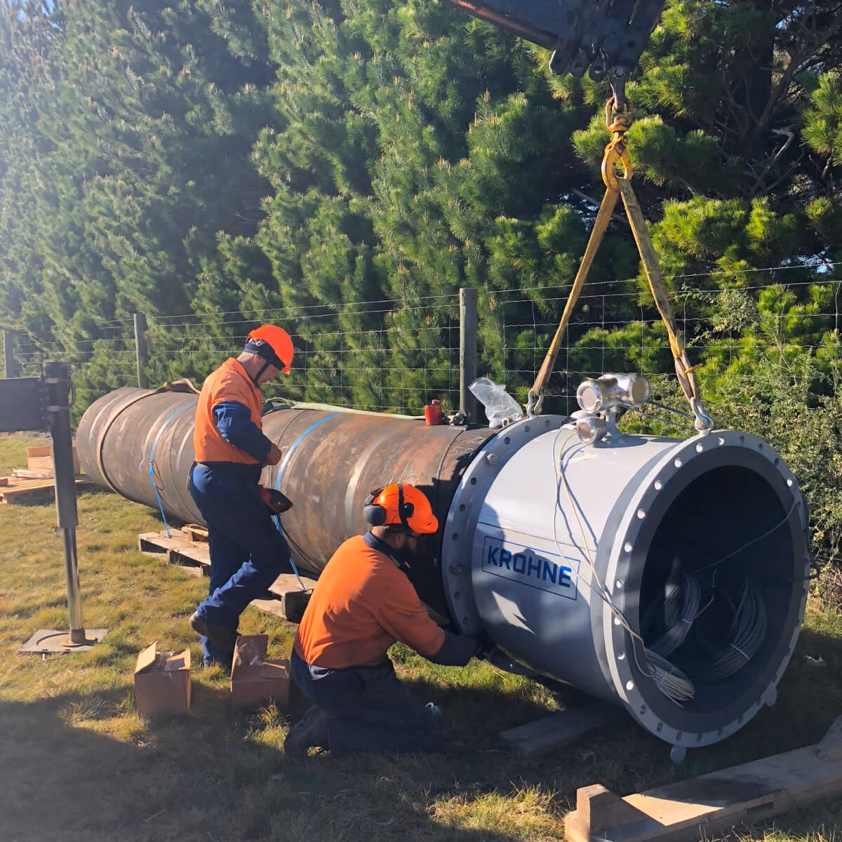 Workers installing a large pipe fitting