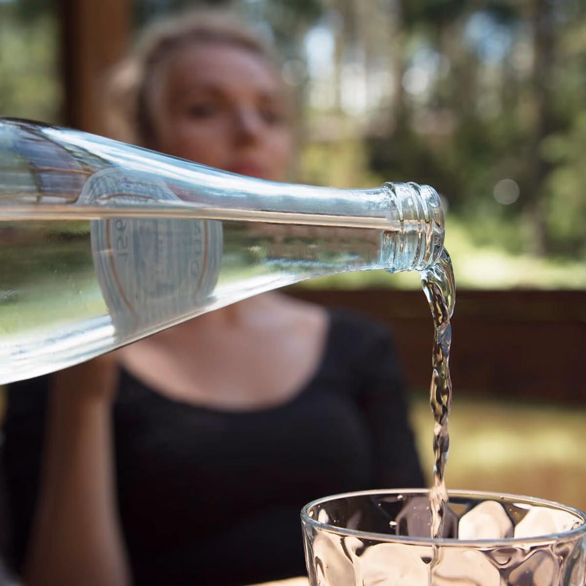 Person pouring drinking water into a glass