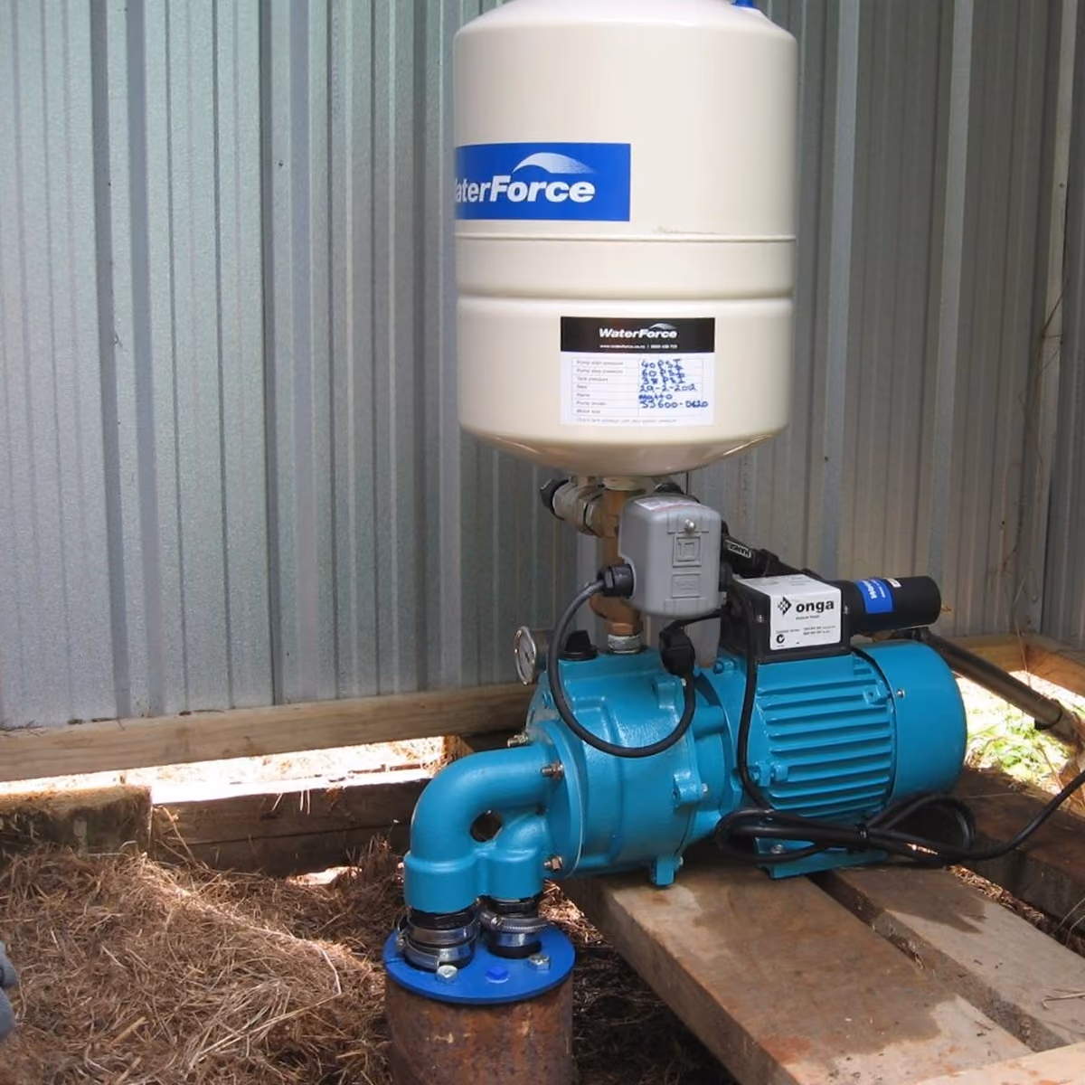 Water pump with pressure tank installed beside a shed